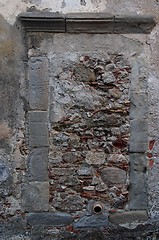 Image showing Old window in gray stone wall blocked by bricks and stones