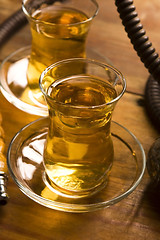 Image showing Cup of turkish tea and hookah served in traditional style