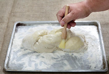 Image showing Brushing egg on bread dough