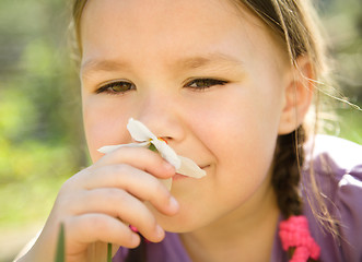 Image showing Portrait of a cute little girl smelling flowers