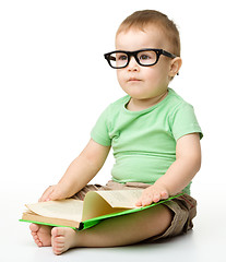 Image showing Cute little boy reads a book