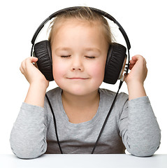 Image showing Cute little girl enjoying music using headphones