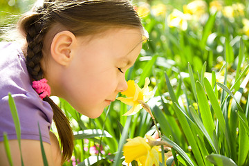 Image showing Portrait of a cute little girl smelling flowers