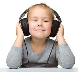 Image showing Cute little girl enjoying music using headphones