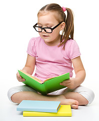 Image showing Cute little girl reads a book wearing glasses