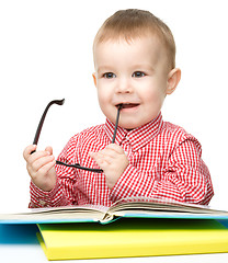 Image showing Little child play with book and glasses