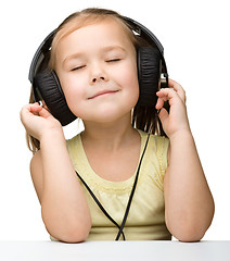 Image showing Cute little girl enjoying music using headphones