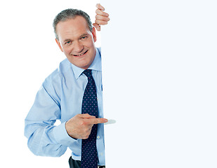 Image showing Businessman peeking behind a whiteboard