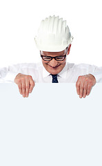 Image showing Aged builder wearning and holding a blank poster