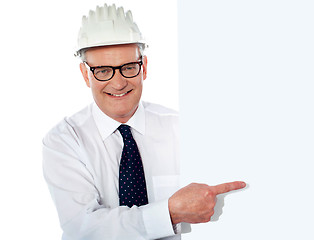 Image showing Senior man in white construction helmet holding placard