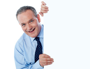 Image showing Man peeking behind empty white billboard