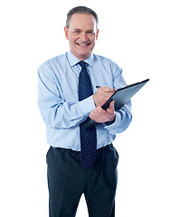 Image showing A smiling ethnic businessman writing on a clipboard folder