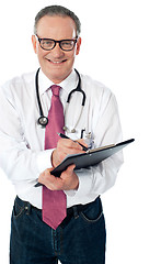 Image showing Happy smiling matured doctor writing on clipboard