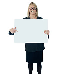 Image showing Corporate woman pointing towards blank billboard