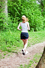 Image showing young woman is jogging in forest