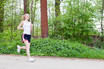 Image showing young woman is jogging in forest