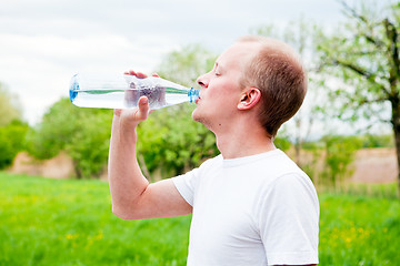 Image showing young jogger is drinking water outdoor
