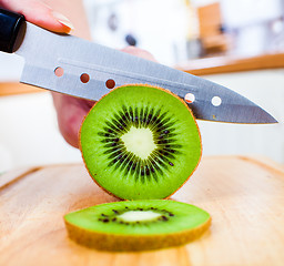 Image showing Woman's hands cutting kiwi