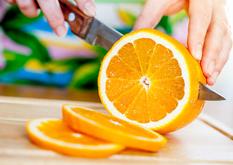 Image showing Woman's hands cutting orange