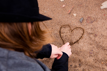 Image showing Young man drawing heart on ground
