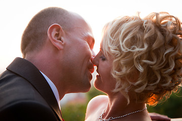 Image showing Bride and groom kissing at sunset