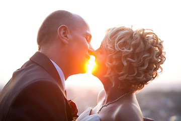 Image showing Bride and groom kissing at sunset