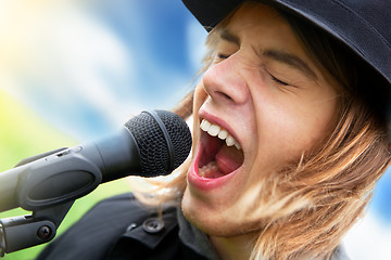 Image showing Young man sings to microphone