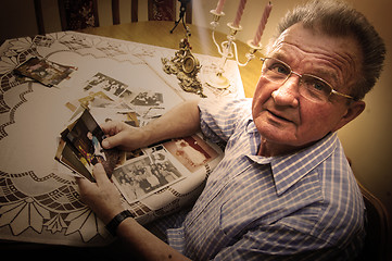 Image showing Senior man looking at old photographs.