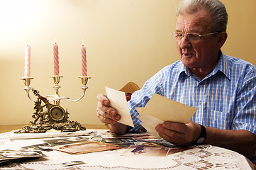 Image showing Senior man looking at old photographs.