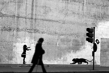 Image showing Silhouette passing by a wall with graffitis