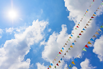 Image showing Blue sky with multi colored party flags hanging 