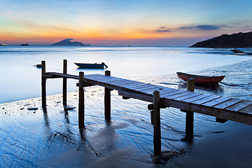 Image showing Sunset at wooden pier along the coast