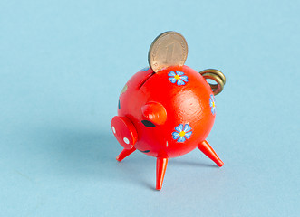 Image showing Red piggybank with pfennig on blue background 