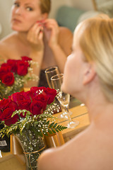 Image showing Blonde Woman Applies Makeup at Mirror Near Champagne and Roses