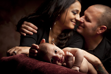 Image showing Mixed Race Couple Lovingly Look On While Baby Lays on Pillow