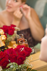 Image showing Blonde Woman Applies Makeup at Mirror Near Champagne and Roses