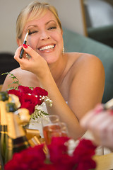 Image showing Blonde Woman Applies Makeup at Mirror Near Champagne and Roses