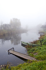 Image showing Wooden boat and bridge on river sunken in fog 