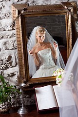 Image showing beautiful bride in white in front of mirror