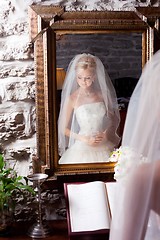 Image showing beautiful bride in white in front of mirror