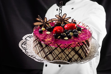 Image showing Holding cake against dark background