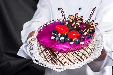 Image showing Holding cake against dark background
