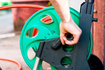 Image showing Man rolling up garden hose