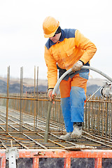 Image showing builder worker pouring concrete into form