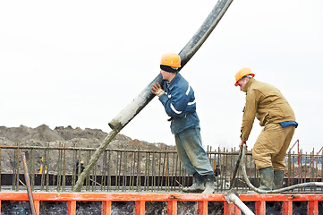 Image showing builder worker pouring concrete into form