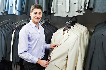 Image showing Young man choosing suit in clothes store