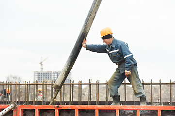 Image showing builder worker pouring concrete into form