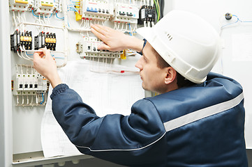 Image showing Electrician with drawing at power line box