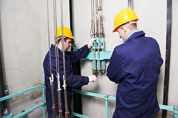 Image showing machinists adjusting lift in elevator hoistway