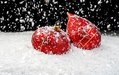 Image showing Snow falling on two red ornaments